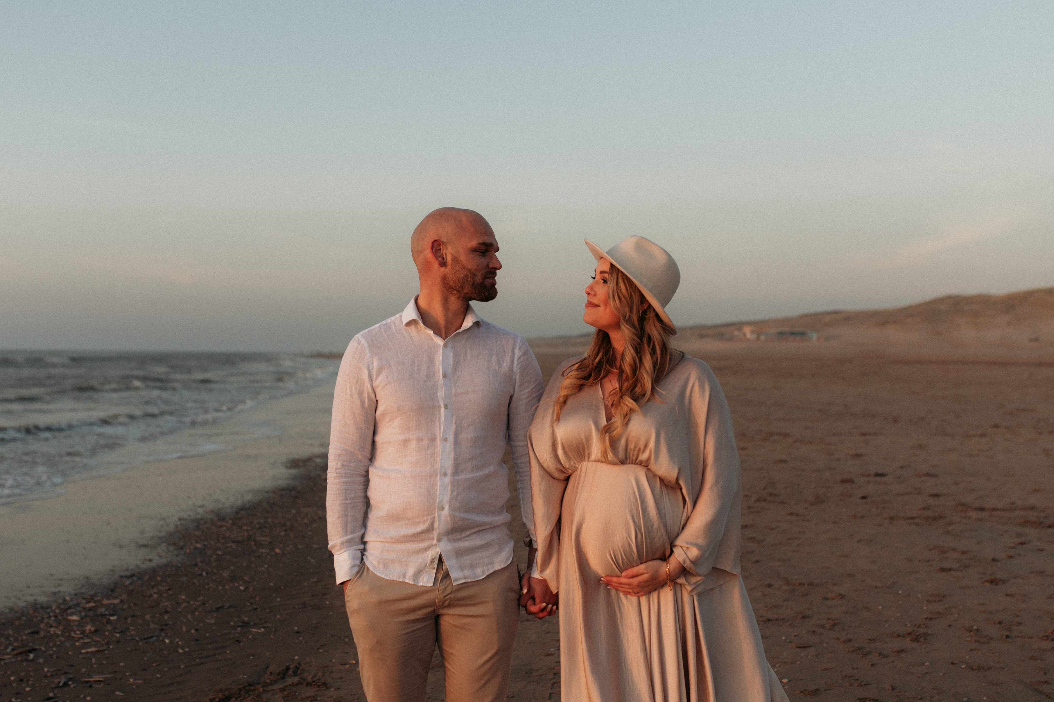 Aanstaande ouders op het strand bij zonsondergang